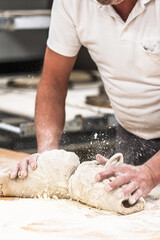 A baker kneads bread dough in the bakery