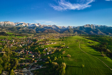 Aerial view of Tatra mountains and Zakopane town at sunset. Panoramic landscape with mountain ranges and green valleys near village. View on Giewont, Poland