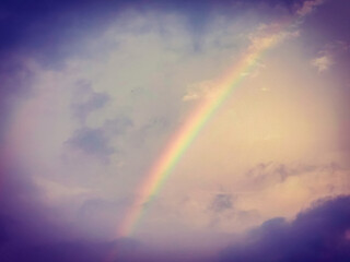 Fototapeta premium Vivid rainbow with dark blue cloud around it. Beautiful rainbow after rain.