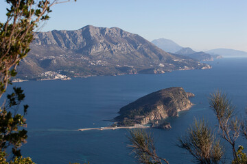 Winter sea colourful landscape with blue water of the Adriatic Sea and the island of St. Nikola near the town of Budva in Montenegro. View from above through the trees. Horizontal