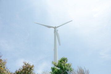 Wind turbine in green field generating renewable energy under blue sky