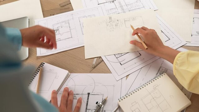 Professional engineer team discussion about house design on meeting table with architectural equipment and building blueprint scatter around at modern office. Focus on hand. Closeup. Delineation.