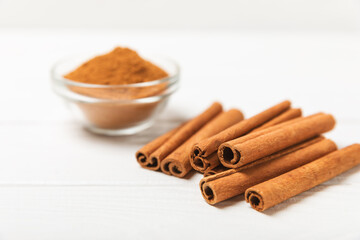Cinnamon sticks on a textured wooden background. Cinnamon roll. Spicy spice for baking, desserts and drinks. Fragrant ground cinnamon. cinnamon powder Close-up. Place for text. copy space