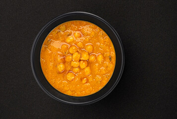 Chickpea cream soup on black background with copy space, top view