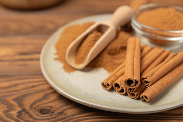 Cinnamon sticks on a textured wooden background. Cinnamon roll. Spicy spice for baking, desserts and drinks. Fragrant ground cinnamon. cinnamon powder Close-up. Place for text. copy space