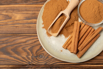 Cinnamon sticks on a textured wooden background. Cinnamon roll. Spicy spice for baking, desserts and drinks. Fragrant ground cinnamon. cinnamon powder Close-up. Place for text. copy space