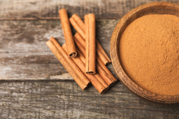 Cinnamon sticks on a textured wooden background. Cinnamon roll. Spicy spice for baking, desserts and drinks. Fragrant ground cinnamon. cinnamon powder Close-up. Place for text. copy space