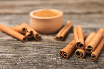 Cinnamon sticks on a textured wooden background. Cinnamon roll. Spicy spice for baking, desserts and drinks. Fragrant ground cinnamon. cinnamon powder Close-up. Place for text. copy space