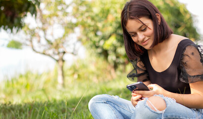 lifestyle: teenager uses smart phone while sitting on grass