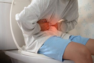 Man sitting on toilet and holding his stomach with stomach pain causes of gastritis or constipation...