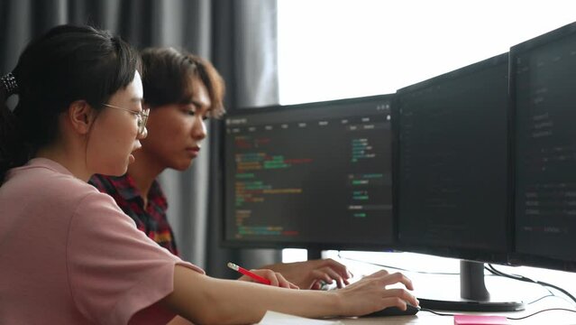 Slow motion back end software developer engineer for computer programming working together on debugging writing computing code, solving complex algorithms display on monitor in office. Burgeoning