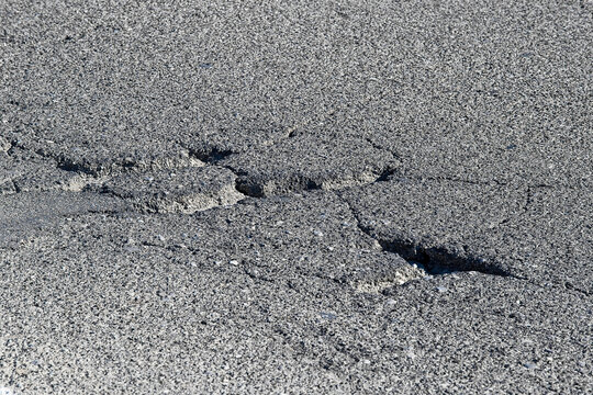 Old asphalt road with dangerously damaged asphalt that has potholes dangerous for the transit of motor vehicles