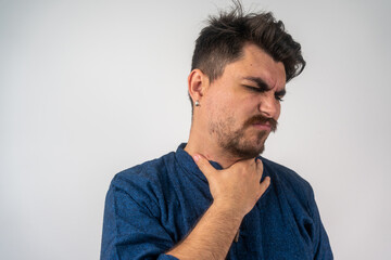 Fototapeta premium Young sick man having sore throat, looking at copy space over grey studio background. Bearded man touching his neck, suffering from throat disorder, tonsillitis, throat cancer, cold