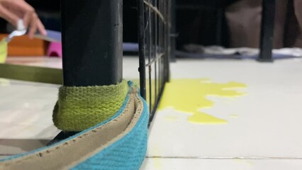 Close up leash tie to pole at home. A naughty untrained white puppy dog peed at home. Yellow urinate of dog on ground floor in background