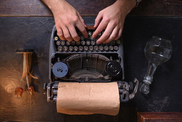 Man typing text on an old typewriter close up. Top view.