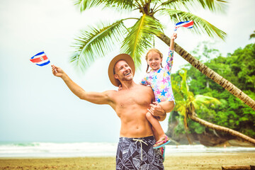 man holding costa rica flag screaming with his daughter on a Costa Rica beach