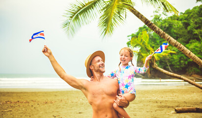 man holding costa rica flag screaming with his daughter on a Costa Rica beach