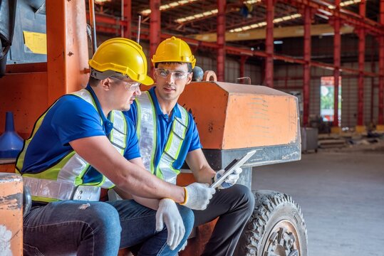 Two workers in a warehouse are looking at a tablet