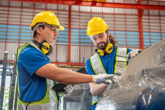 Two workers in a warehouse are inspecting a product.