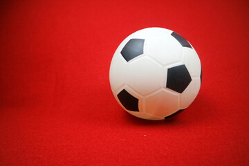 a small white and black toy rubber ball. Red background