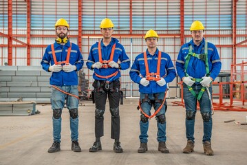 Four construction workers wearing hard hats and safety gear posing for a photo.