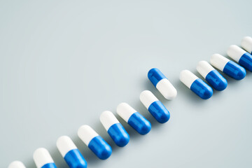 A row of white and blue pills on a blue background.