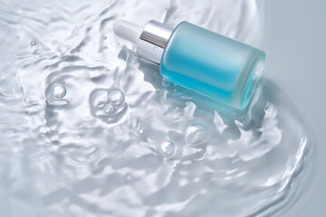 Bottles of cosmetics with a dropper in water on a blue background.