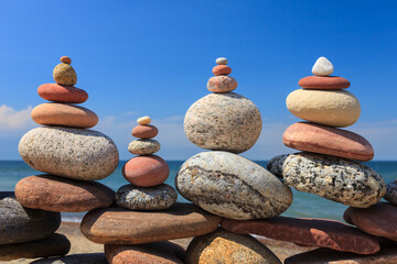 Four Rock zen pyramids of colorful pebbles standing on the beach, on the background of the sea....