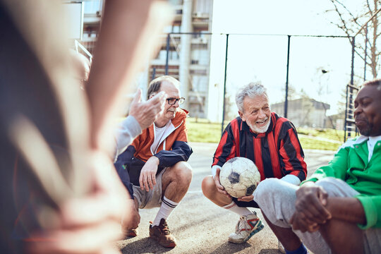 Senior soccer team taking a break and strategizing during game on urban court