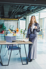 Young female lawyer drinks coffee and looks at notes in a notebook. A business woman works in a modern office