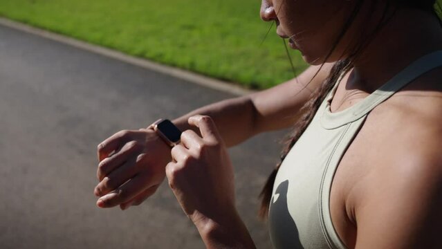 Close up of a young Latina sportswoman checking her heart rate on smart watch. Fitness people monitoring training with a digital device. Apps for athletes. Timing the run on her wearable smartwatch.