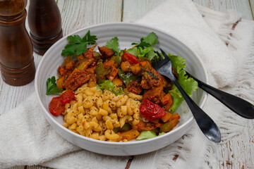 Vegan Pasta bowl consisting of roasted seitan with pepper, macaroni and hebs