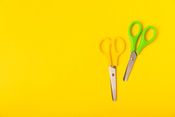 Bright children's scissors on a colored paper background. Stationery. Goods for school. Place for...
