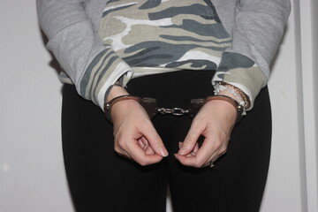 A blonde woman stands with her hands handcuffed in front of her after being arrested