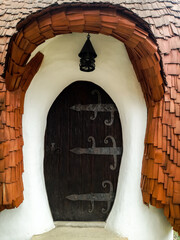 Enchanted Entryway: Mystical Arched Door in old Cottage. Charming arched wooden door set in quaint...