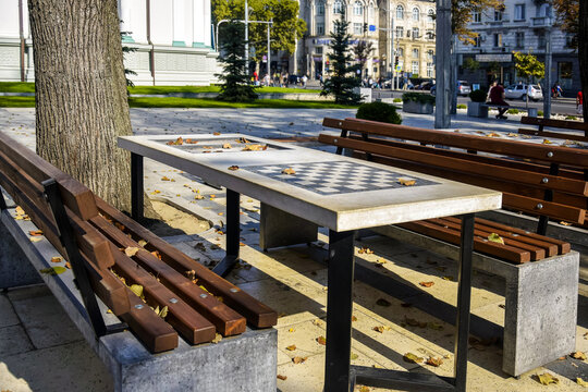 Chess Tables Await Players in a City Park. Autumnal cityscape.