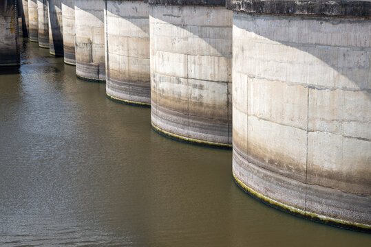 The water is calm and the river is surrounded by concrete walls, damb contention