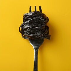 Minimal concept of black spaghetti pasta on fork. Yellow solid background. Copy space. Italian food. Restaurant. 