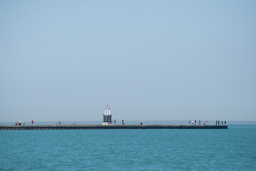 A pier with a lighthouse and a group of people standing on it