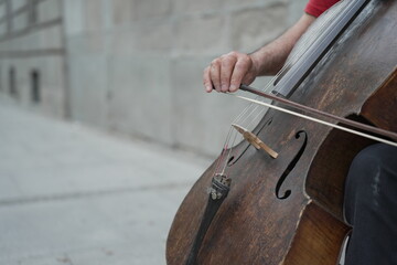 Street Serenade. Anonymous Hands Skillfully Playing a Double Bass Outdoors. Close-up of a man’s...
