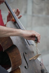 Street Serenade. Anonymous Hands Skillfully Playing a Double Bass Outdoors. Close-up of a man’s hands playing a double bass on the street.