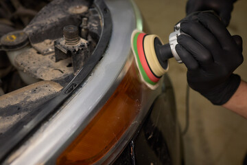Fototapeta premium Person using a machine to polish automotive lighting on a car headlight