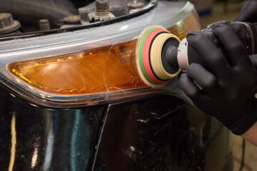 Person using a machine to polish automotive lighting on a car headlight