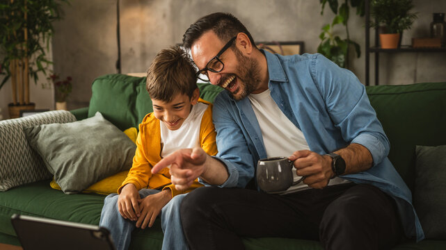 Father and son watch movie or cartoon on tablet at home