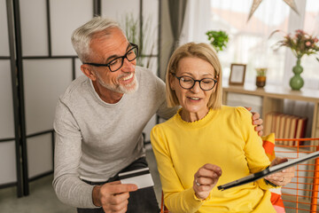 Mature caucasian husband and wife shopping online sit at home