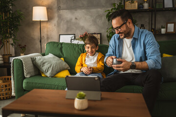 Father and son watch movie or cartoon on tablet at home