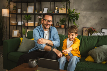 Father and son watch movie or cartoon on tablet at home