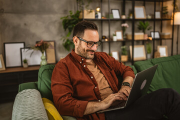 Adult caucasian man sit at home and look, read on laptop at home