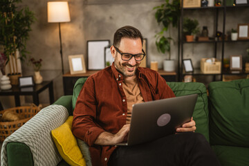 Adult caucasian man sit at home and look, read on laptop at home