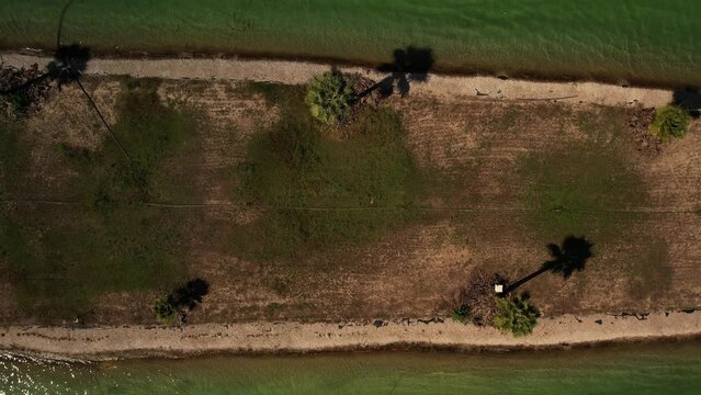 top view of the wakepark. the drone rises above the wakepark wakeboarders ride in a circle on the water in the middle palm trees grow on the island. High quality 4k footage